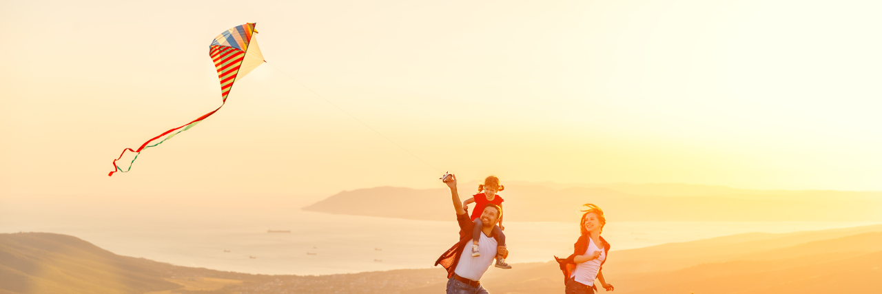 Quality of Life Improvements for Children With Angelman Syndrome Happy family father of mother and child daughter launch a kite on nature at sunset