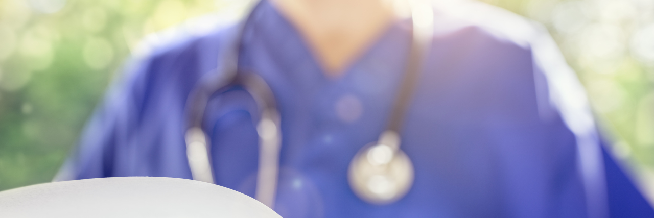 Doctor in scrubs uniform reading patient notes or medical chart