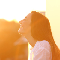 Woman looking towards the sun and smiling.