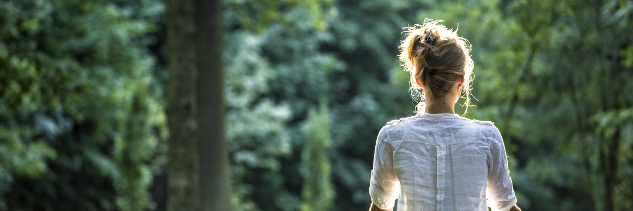 My Journey to Accept My Mast Cell Activation Syndrome Diagnosis Young blonde woman meditating in the park while the sunshines down on her.