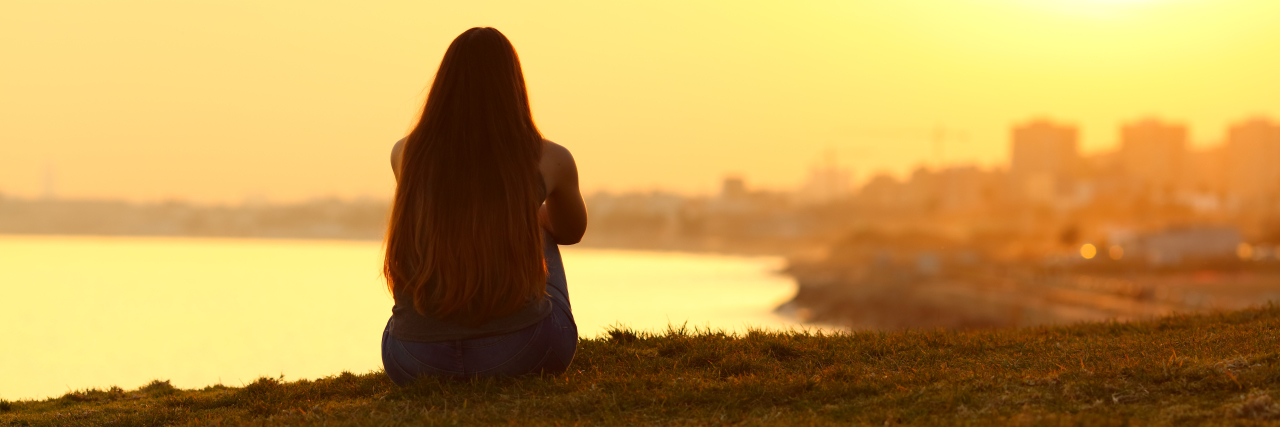 woman watching a sunset on the city with a warm light in the background