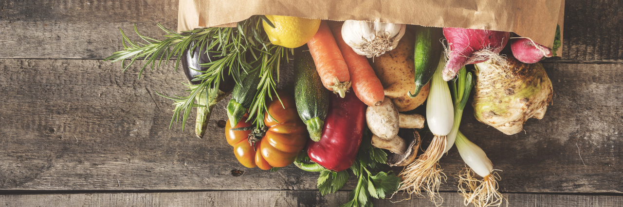 brown bag full of vegetables spilling out on a table