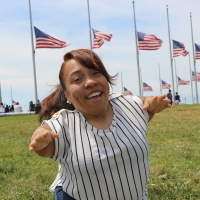 Monique sitting in the grass with a row of American flags behind her.