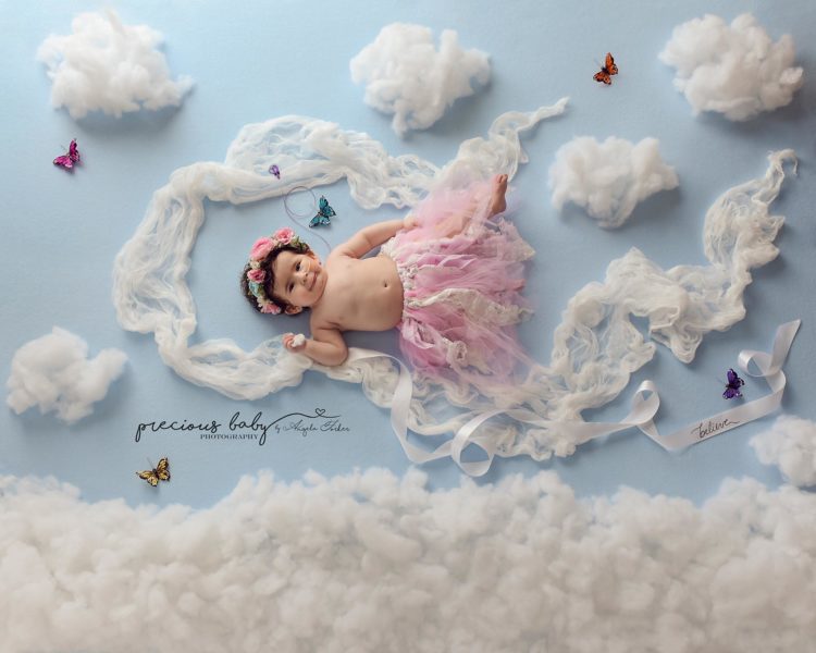 Baby girl flying through the sky among clouds, she is wearing a pink tutu.