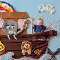 Baby pictures in a "Noah's Ark" scene. Boat has a giraffe, an elephant, a lion and a rainbow.