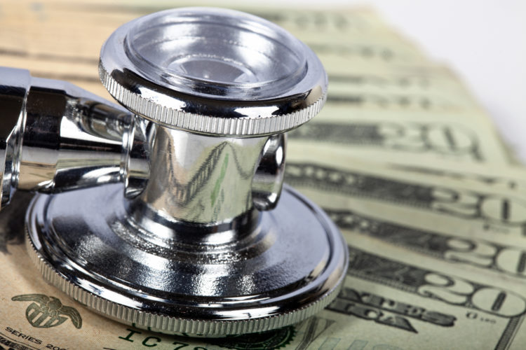 Macro shot of a stethoscope on money. Focus is on the stethoscope.