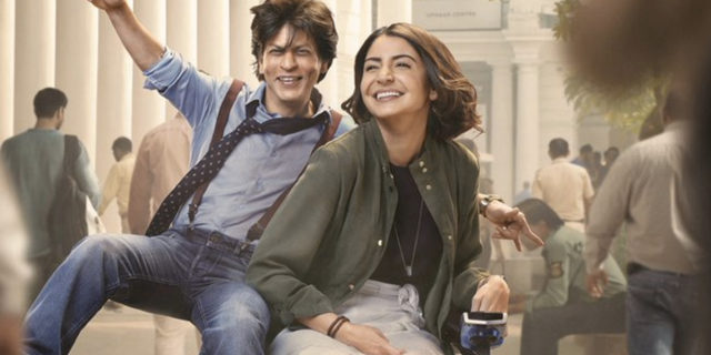Shah Rukh Khan and Anushka Sharma. Sharma is driving a power chair, Khan is riding on the side.