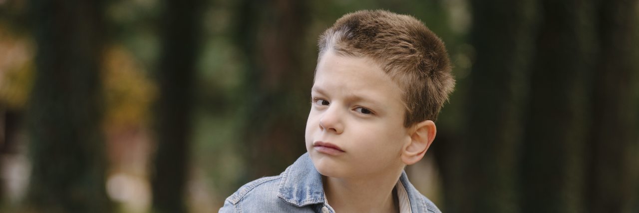 Little boy with CP looking at camera, he is not smiling.