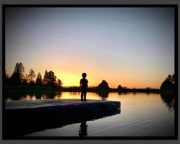 Photo of Tonya Mae Wilson's sun at the end of a dock overlooking water at sunset