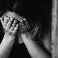 black and white photo of woman with hands covering face depression