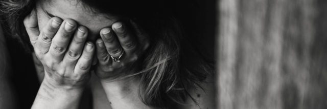 black and white photo of woman with hands covering face depression