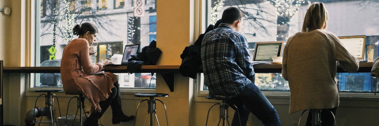 Advice for Freshmen Week If You Live With an Illness College students sitting at a cafe, working on their computers by a bar near a window.