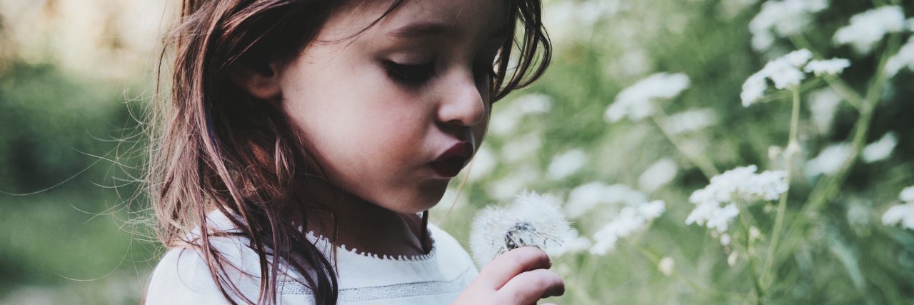 8 Ways a Child’s Anxiety Can Show Up as Something Else girl in garden blowing on a flower