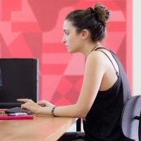 Woman working in office with red wall behind her