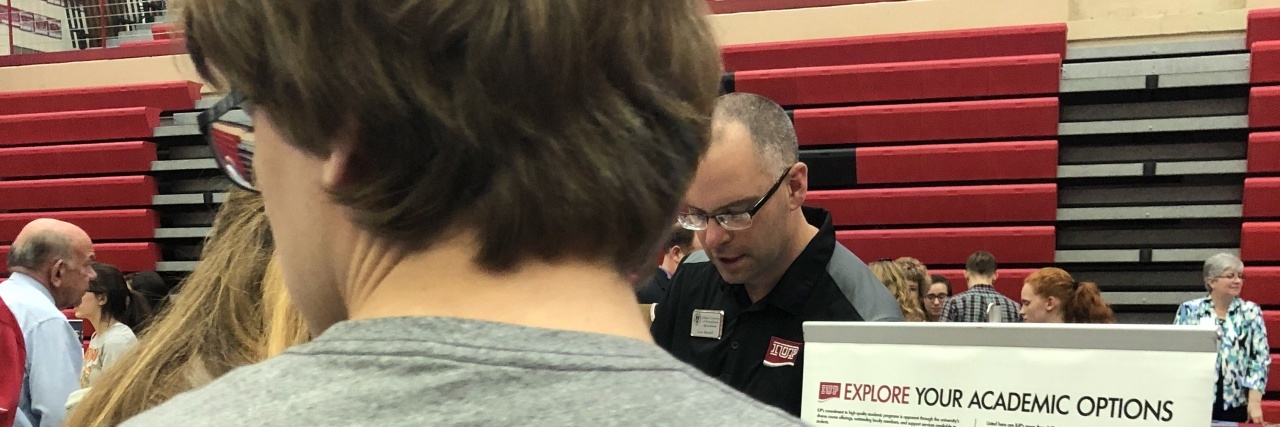 Why Remembering the Hard Days Are a Must Parenting an Autistic Teen Back of tall teen at a college fair waiting to talk to a college representative