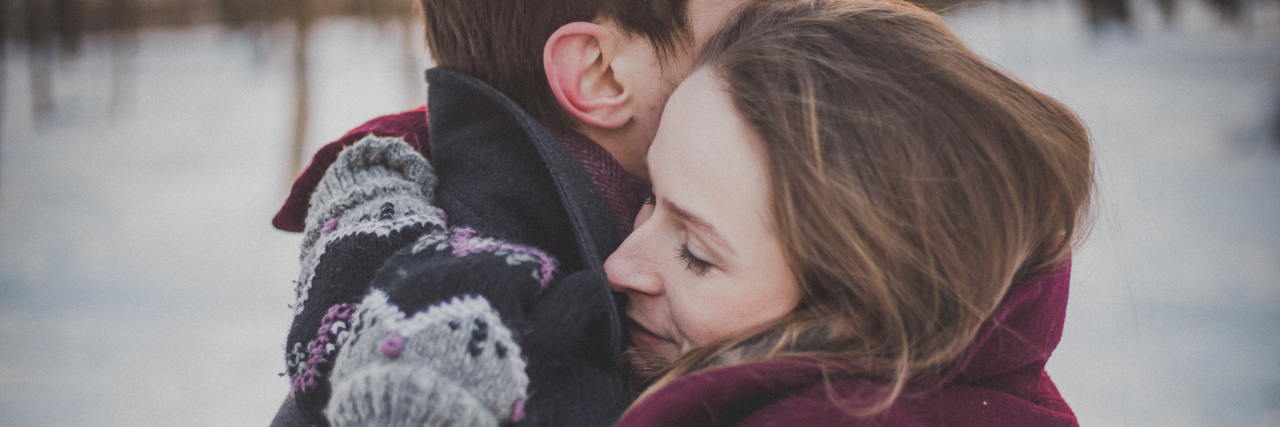 photo of man and woman hugging in snow