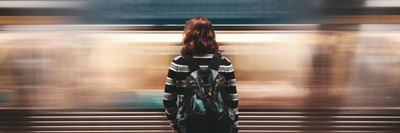 woman standing still in front of moving blurred train