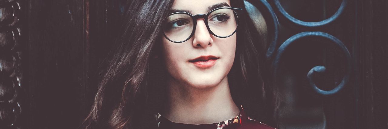 What Choosing Mental Health Recovery Is Like Woman wearing glasses and standing in front of iron gate