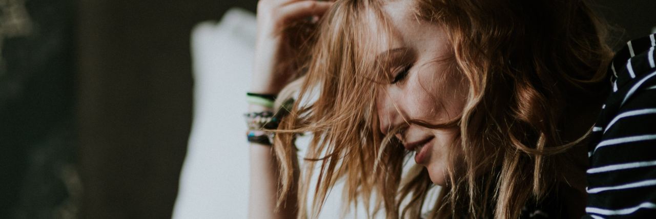 What I've Learned About Life With Crohn's Disease blonde woman lying on her bed on her stomach and smiling