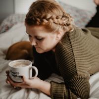 woman lying on bed holding mug of coffee saying "morning pumpkin"