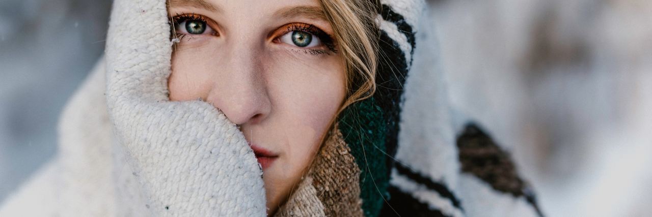 Basic Self-Care for Beginners Woman wrapped in blanket looking into camera