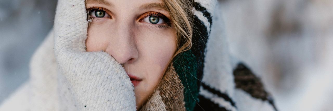 Woman wrapped in blanket looking into camera