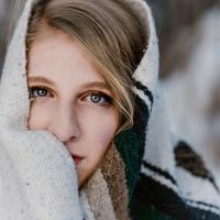 Woman wrapped in blanket looking into camera