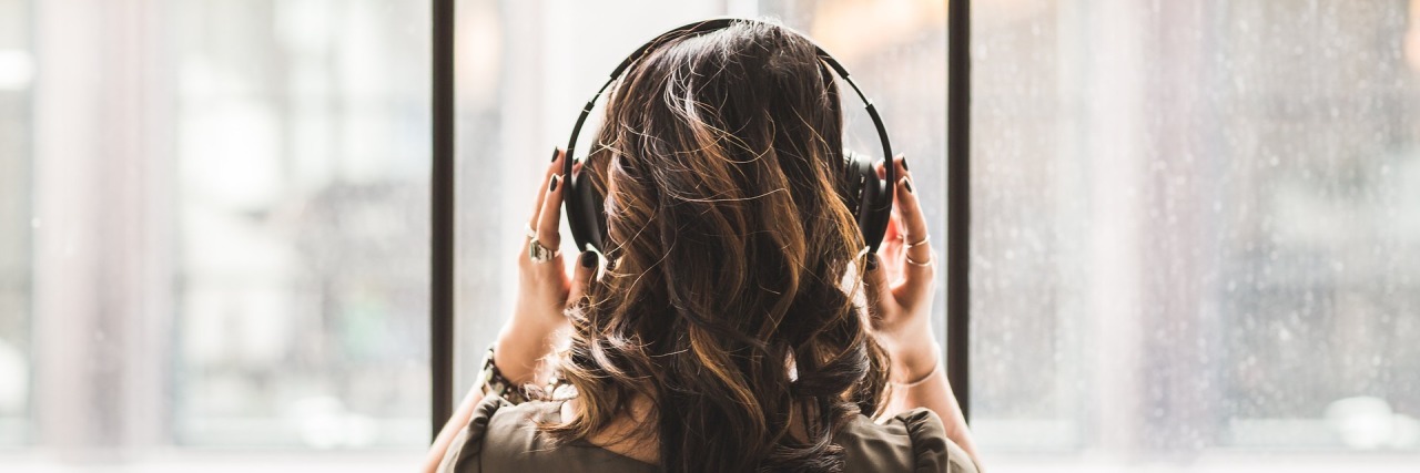 Songs That Get Real About Depression woman wearing headphones looking out of high windows