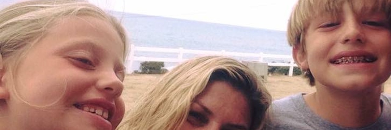 What I Do Not Want to Hear as a Parent of Kids With Hearing Loss Mother smiling at camera between her two children, who are smiling to the side. The ocean is behind them.