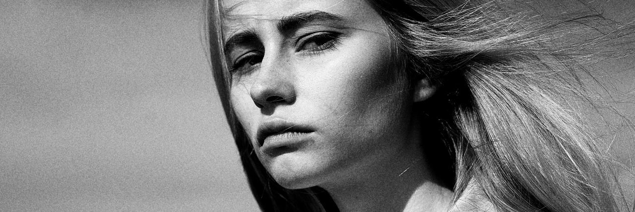 When Doctors Tell You Not to Talk About Your Pain black and white photo of a woman wearing a coat and standing outside