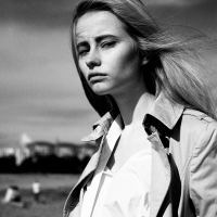 black and white photo of a woman wearing a coat and standing outside