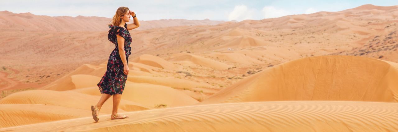 woman in desert searching with hand raised to shield eyes