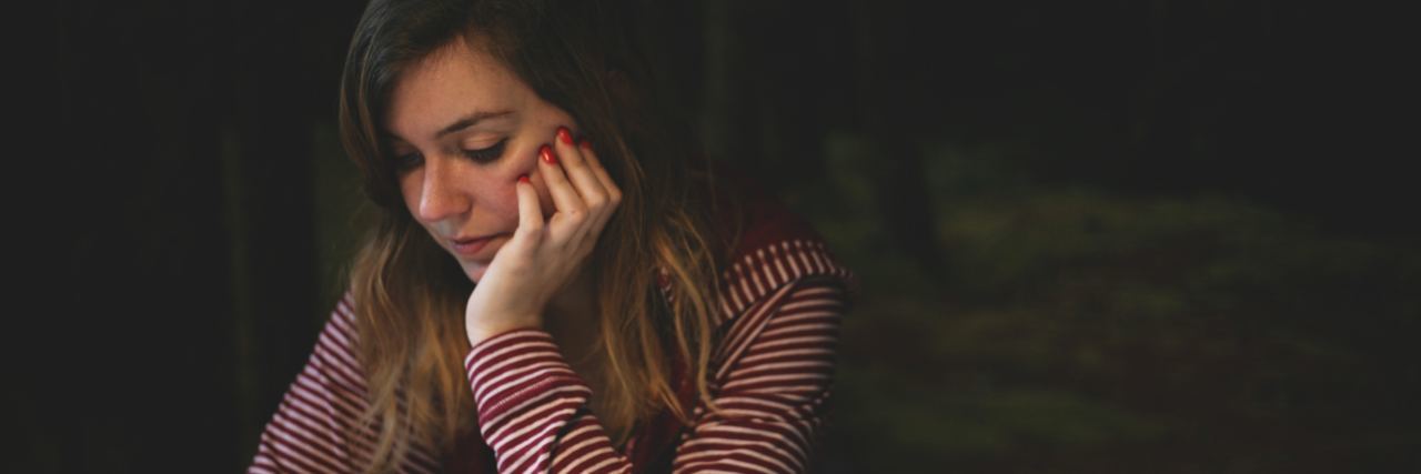 Difference Between Introvert and Social Anxiety young woman sitting at table with phone looking anxious