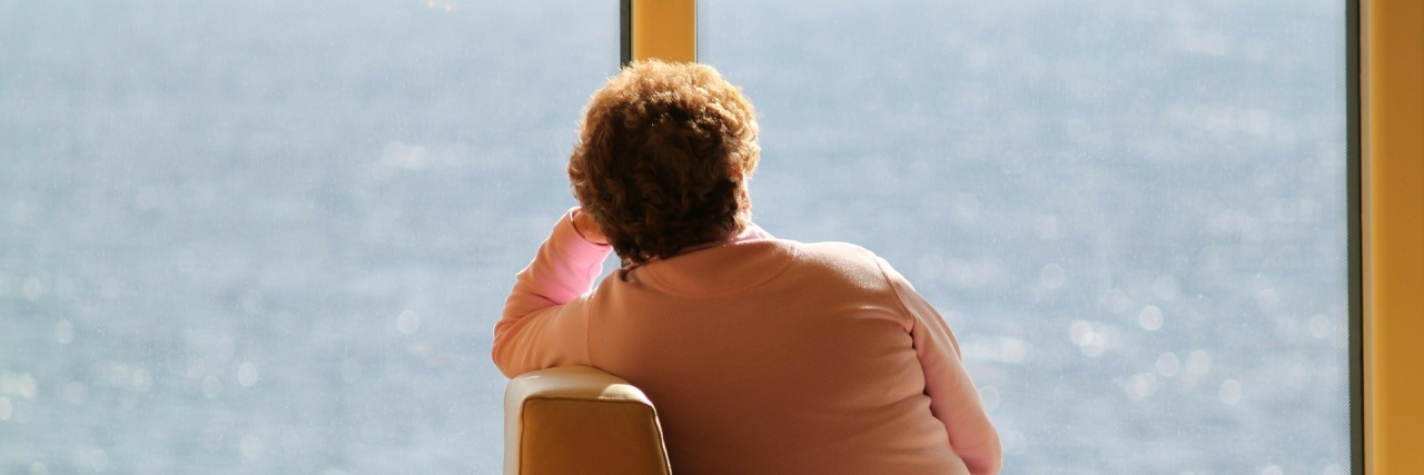 woman with breast cancer alone on a train looking at the ocean