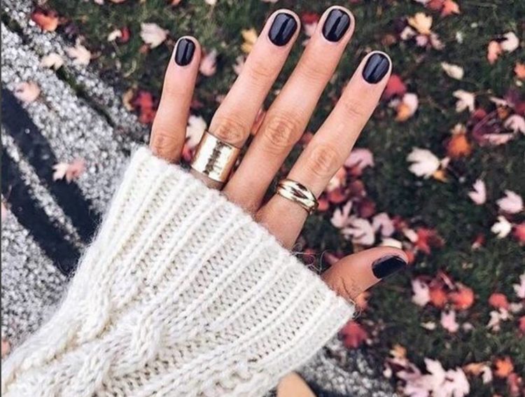 hand with black manicure wearing sweater