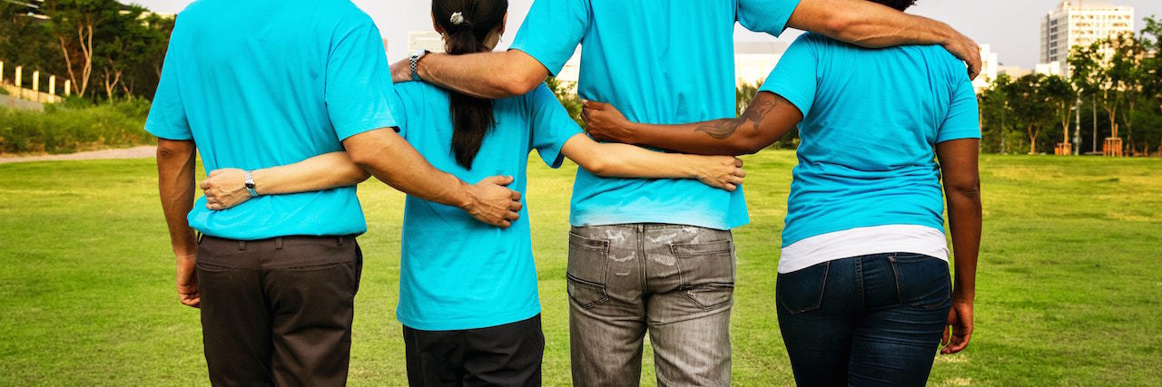 How to Tell Someone You Have a Mental Illness A group of people talking with their arms around each other, facing away