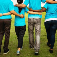 A group of people talking with their arms around each other, facing away