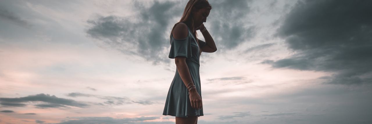 Depression Always Comes Back Into My Life photo of young woman standing on rock by ocean silhouetted by sunset sky