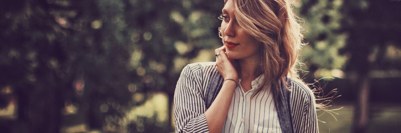 How to Help Someone After a Traumatic Brain Injury woman in front of trees looking away from camera with hand to neck