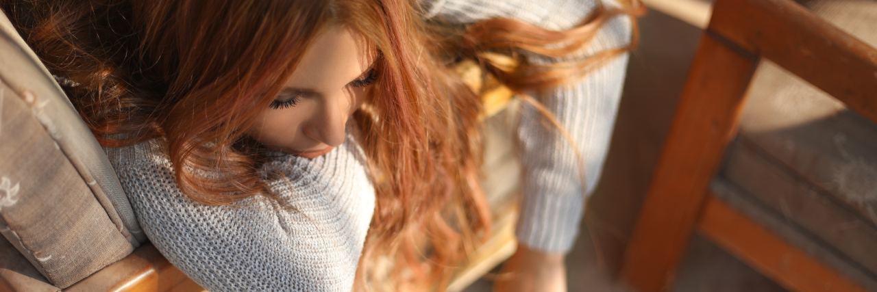 How to Survive Bad Days With Chronic Illness photo of redhead woman lying on sofa bathed in light looking bored or tired