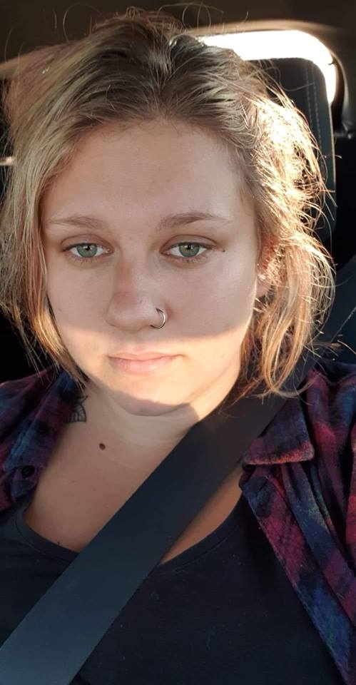 woman wearing a plaid shirt and taking a selfie in her car