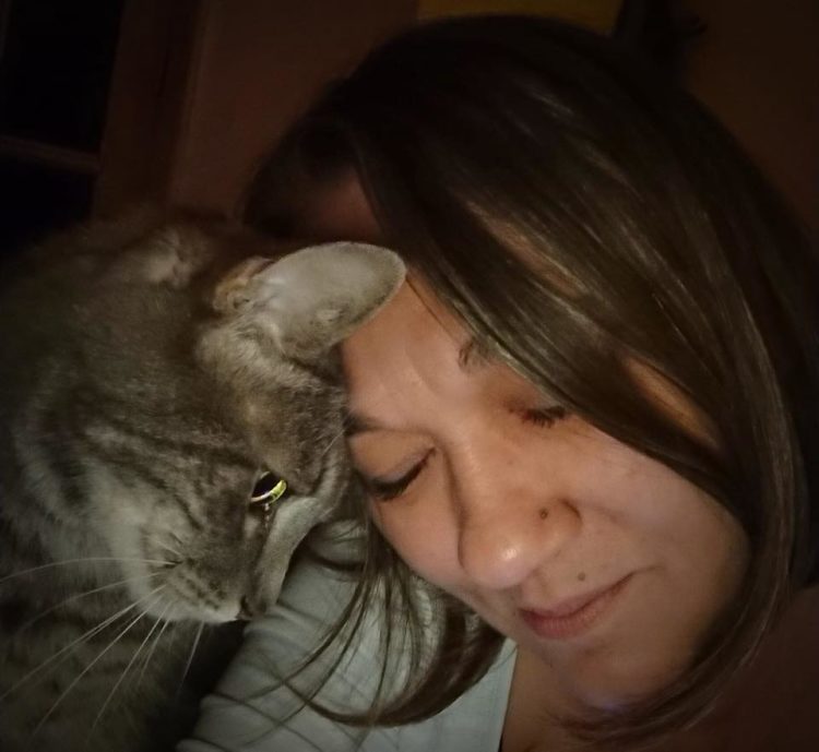 woman closing her eyes cuddling cat