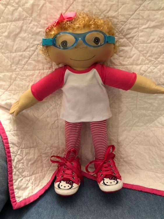 A Doll Like Me doll with glasses, blonde hair and Hello Kitty sneakers