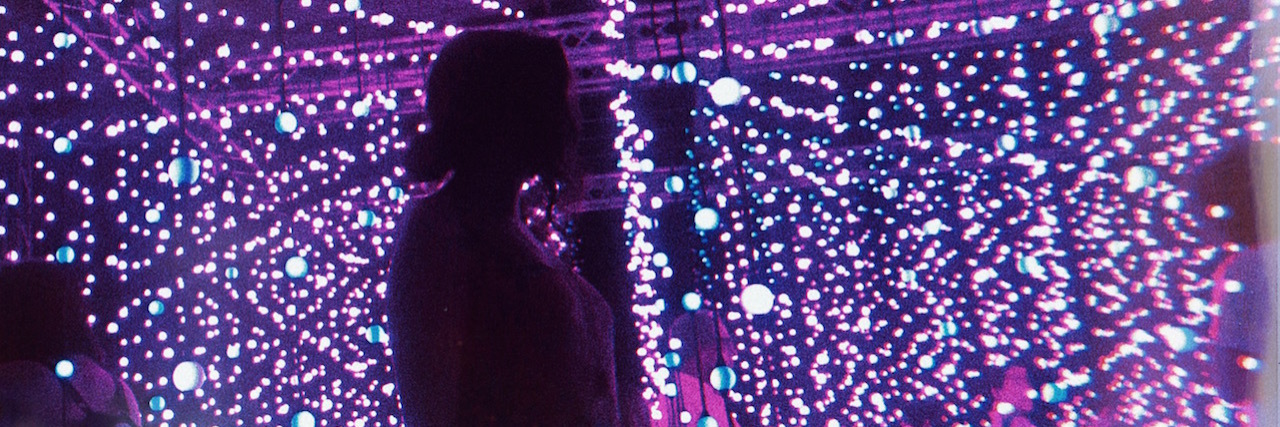 A silhouette of a woman in front of purple lights