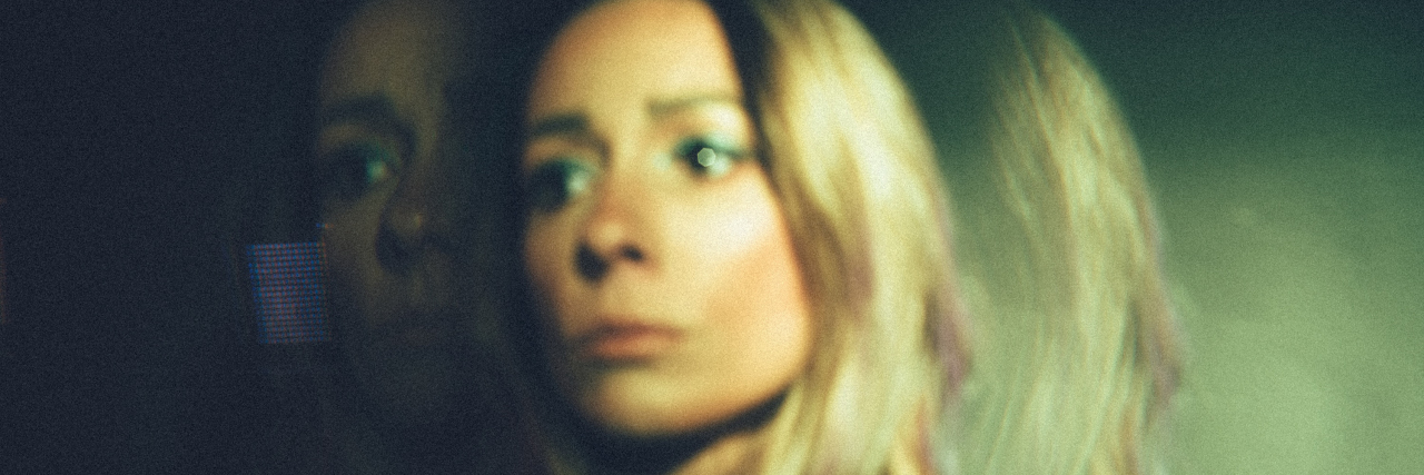 photo showing blonde woman blurred and distorted by double exposure in green light, looking upset