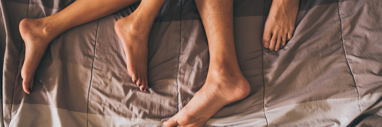How Bipolar Disorder Affects Sex Close up of the legs of a couple on the bed.