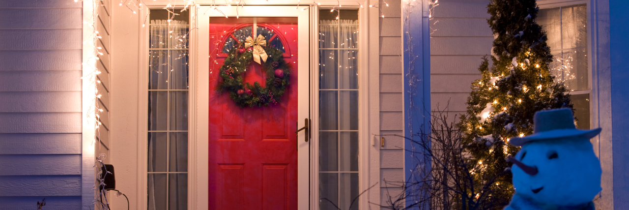 House front door decorated with Christmas wreath, lights and a snowman.