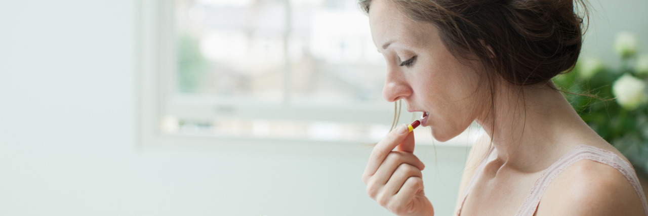 When I Was Offered Diet Pills While in Eating Disorder Recovery photo of upset woman taking pill