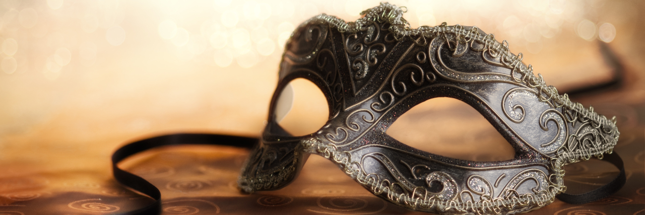 The Long-Term Impact of Autistic Masking Carnival mask sitting on a table.