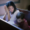 Woman looking over at son sitting on church pews.